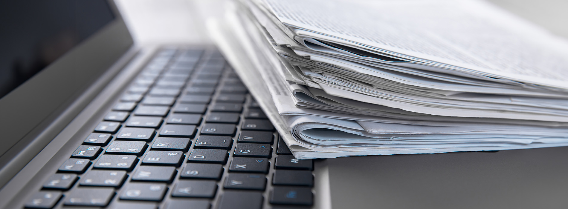 A stack of papers on top of a laptop computer.