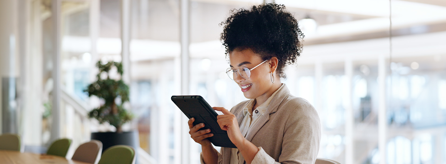 A woman in a professional setting using her phone while seated at a table with modern decor.
