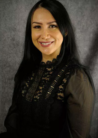A woman with dark hair posing against a backdrop.