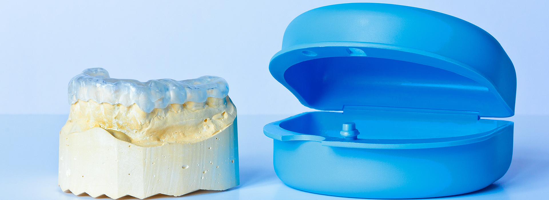 The image displays two dental implants: one is a blue model and the other appears to be a real implant with a visible screw, placed on a white background.