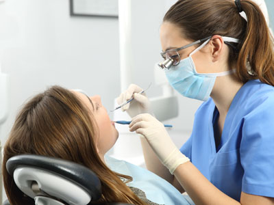 In the image, a dental hygienist is performing a procedure on a patient s teeth while they are seated in a dental chair.