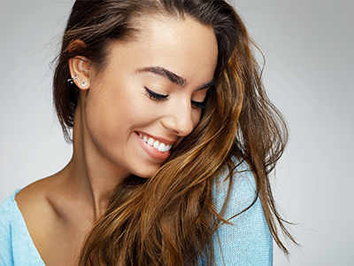 The image displays two separate photographs of a woman with long hair smiling, set against a light background, with no visible text or additional context provided.