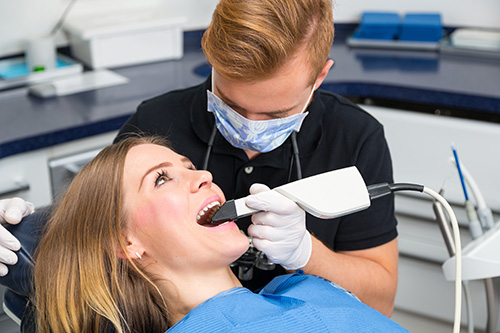 A dental hygienist performing dental work on a patient in an office setting.