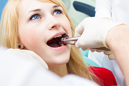 Woman receiving dental treatment with a dental hygienist, sitting in a dentist s chair while getting her teeth cleaned.