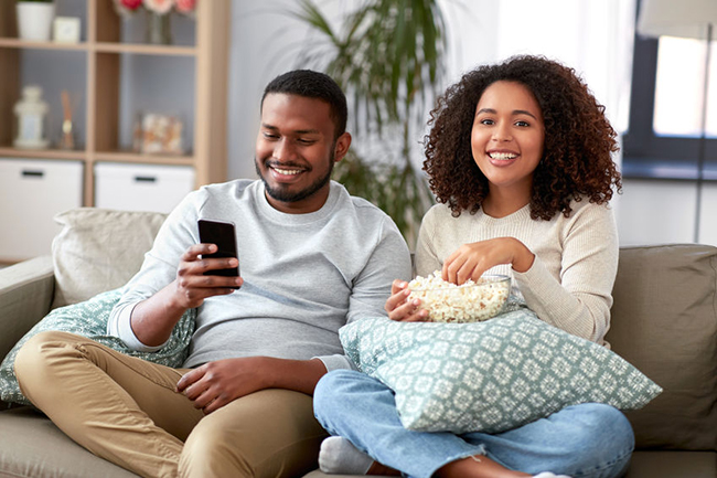 A couple sitting on a couch, enjoying a movie night together.